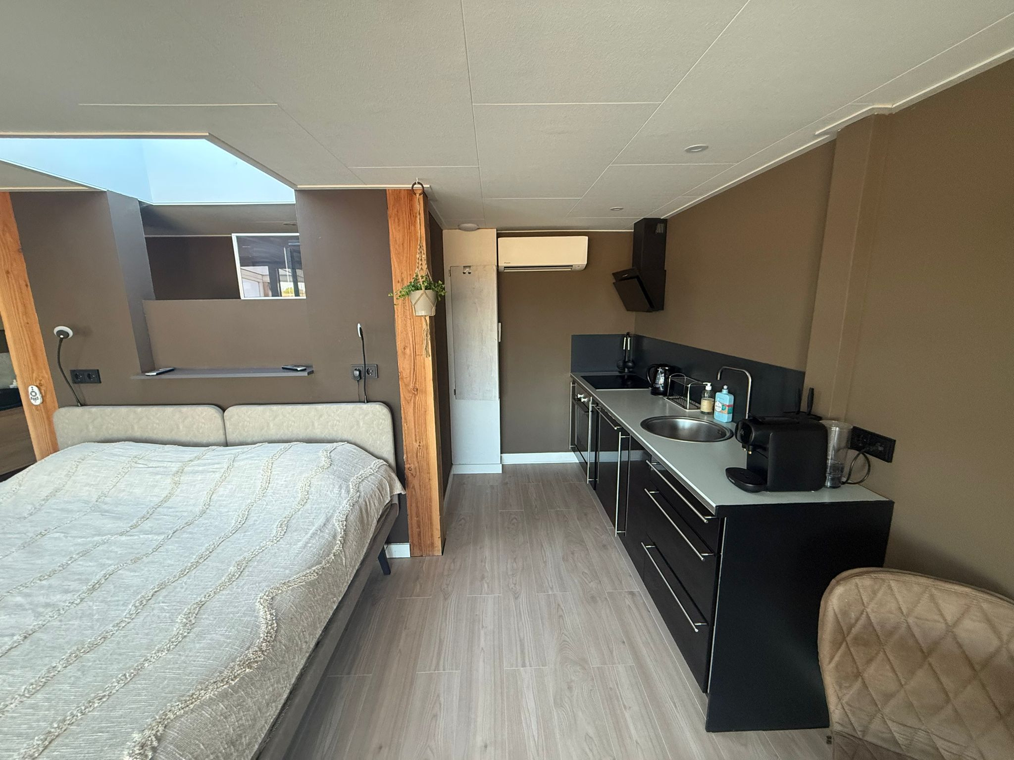 Interieur van het huisje met tweepersoonsbed, kitchenette en houten vloer